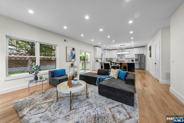 living room featuring light wood-style flooring, baseboards, and recessed lighting