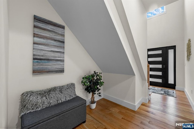 entrance foyer featuring wood finished floors, baseboards, and vaulted ceiling