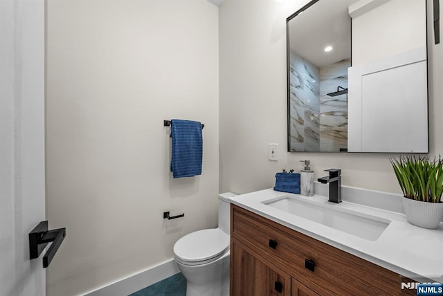 bathroom with toilet, vanity, a shower, and baseboards