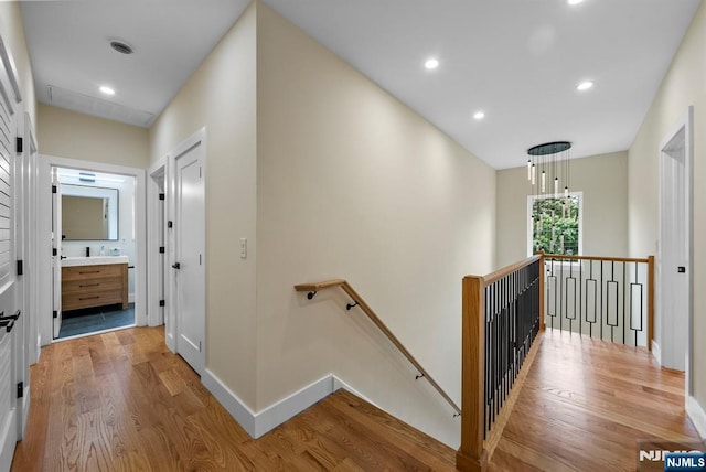 corridor featuring an upstairs landing, light wood-style floors, recessed lighting, and baseboards