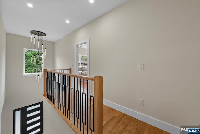 hall with an upstairs landing, wood finished floors, recessed lighting, and baseboards