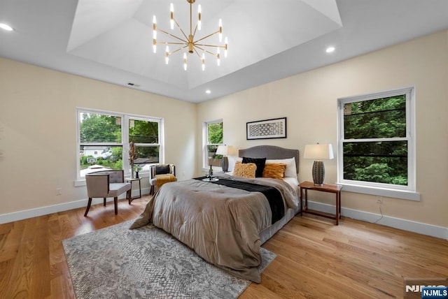 bedroom with a chandelier, a tray ceiling, baseboards, light wood finished floors, and recessed lighting