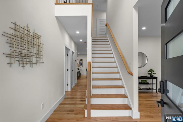 stairway with wood finished floors, baseboards, and recessed lighting