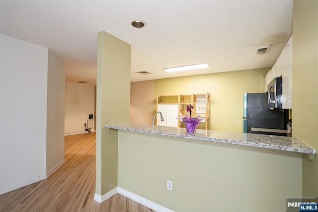 364 Palisade Ave Unit 4C, Cliffside Park, NJ 07010 - kitchen featuring freestanding refrigerator, a peninsula, wood finished floors, stainless steel microwave, and white cabinets