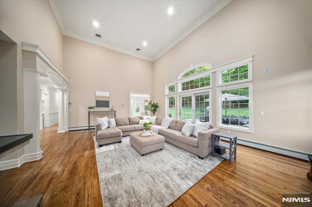 17 Sunset Ln, Upper Saddle River, NJ 07458 - living room featuring baseboard heating, a towering ceiling, ornamental molding, wood finished floors, and plenty of natural light