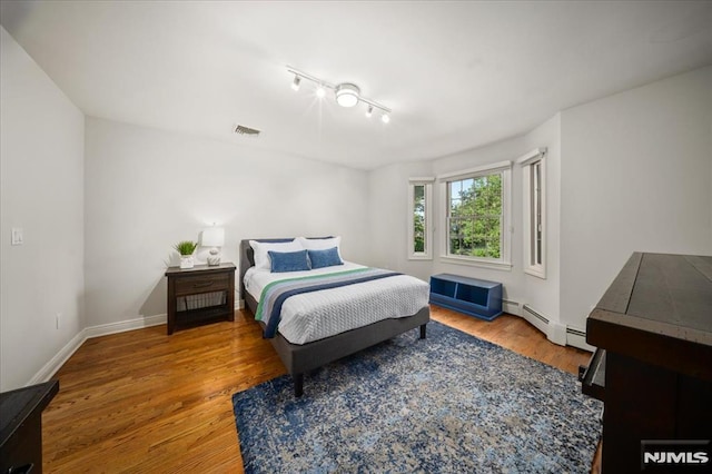 17 Sunset Ln, Upper Saddle River, NJ 07458 - bedroom featuring wood finished floors, rail lighting, baseboards, and baseboard heating