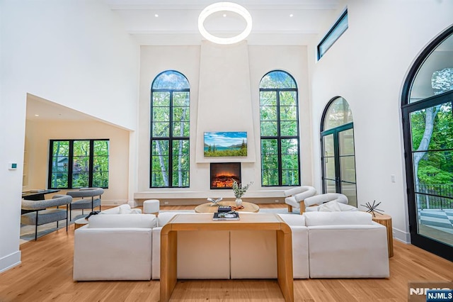 living room with a high ceiling, wood finished floors, and a lit fireplace
