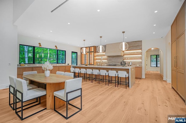 dining area with arched walkways, light wood finished floors, plenty of natural light, and recessed lighting