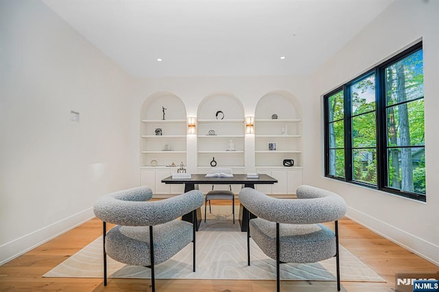 dining space with baseboards, built in features, and light wood finished floors