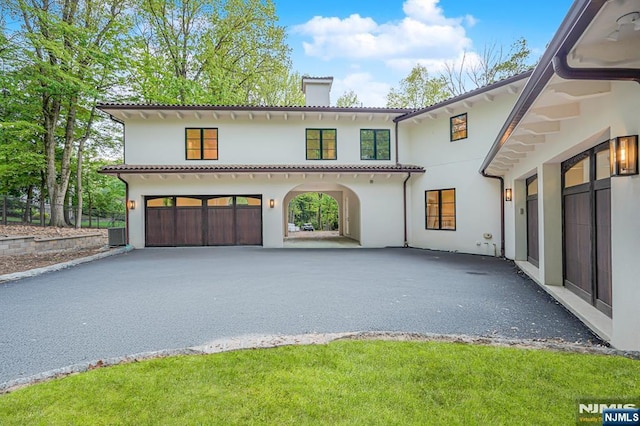 view of front of home featuring a chimney, asphalt driveway, stucco siding, and a garage