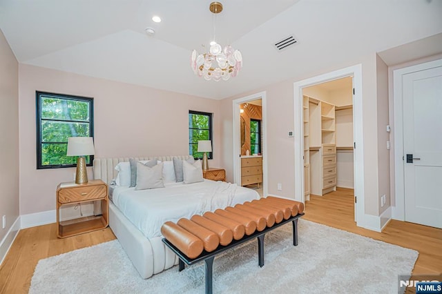 bedroom with light wood finished floors, a chandelier, and multiple windows