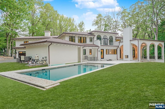back of property featuring a chimney, a balcony, a patio area, an outdoor pool, and stucco siding