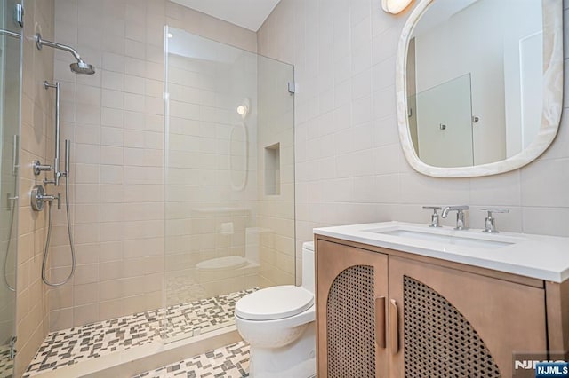 full bath featuring tile walls, toilet, tiled shower, and vanity