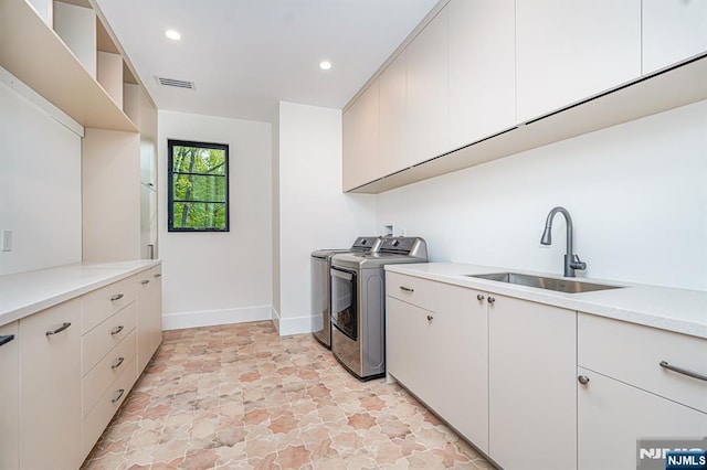 laundry room featuring separate washer and dryer, cabinet space, baseboards, recessed lighting, and light stone finish flooring