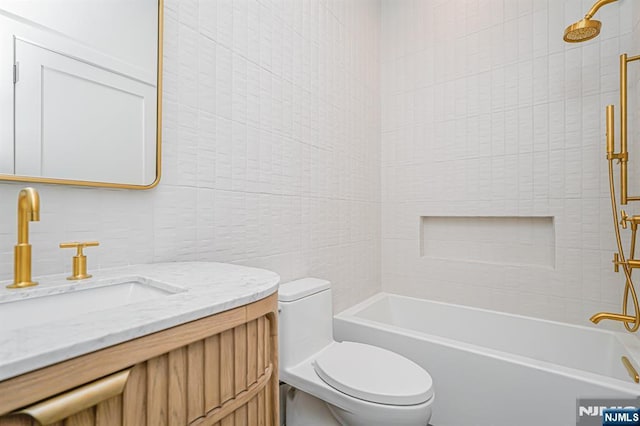 full bath featuring tile walls, toilet, vanity, and shower / tub combination