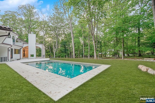 outdoor pool featuring a lawn and a patio