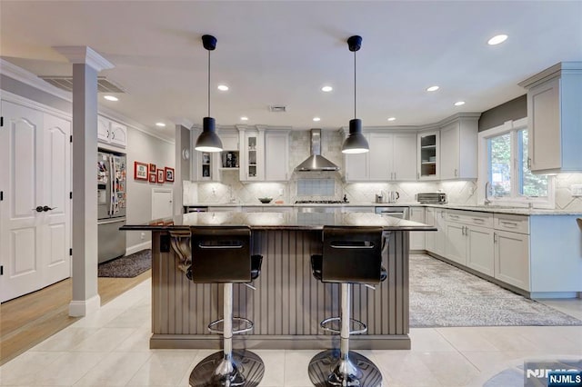 155 W Clinton Ave, Tenafly, NJ 07670 - kitchen featuring wall chimney exhaust hood, stainless steel appliances, a breakfast bar, a kitchen island, and crown molding