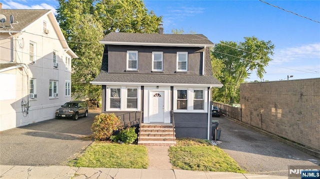 traditional-style home featuring asphalt driveway, a shingled roof, and fence