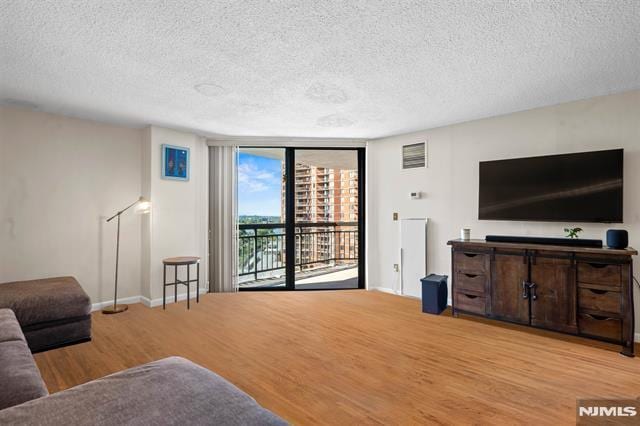 708 Harmon Cv, Secaucus, NJ 07094 - living area with wood finished floors, a textured ceiling, baseboards, and a wall of windows