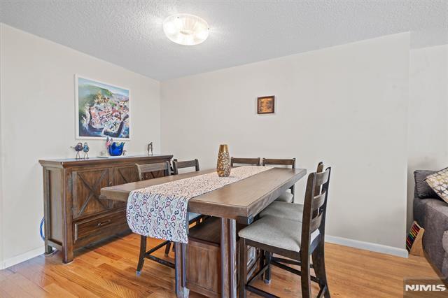 708 Harmon Cv, Secaucus, NJ 07094 - dining area with light wood-style floors, baseboards, a textured ceiling, and bar