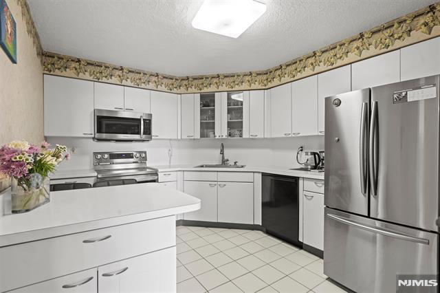 708 Harmon Cv, Secaucus, NJ 07094 - kitchen featuring stainless steel appliances, a sink, a textured ceiling, light countertops, and light tile patterned flooring