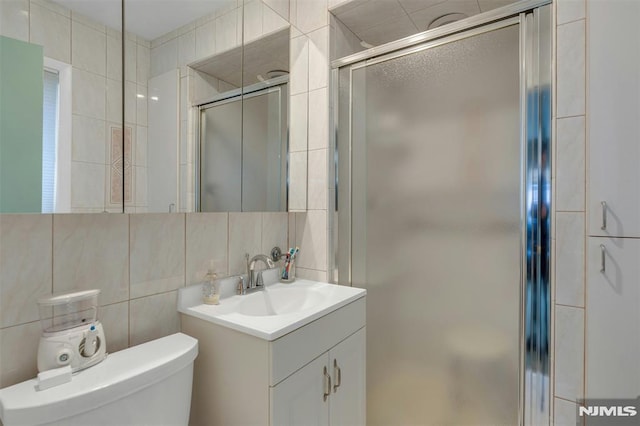 526 Rutland Ave, Teaneck, NJ 07666 - bathroom with tile walls, vanity, toilet, a shower stall, and decorative backsplash