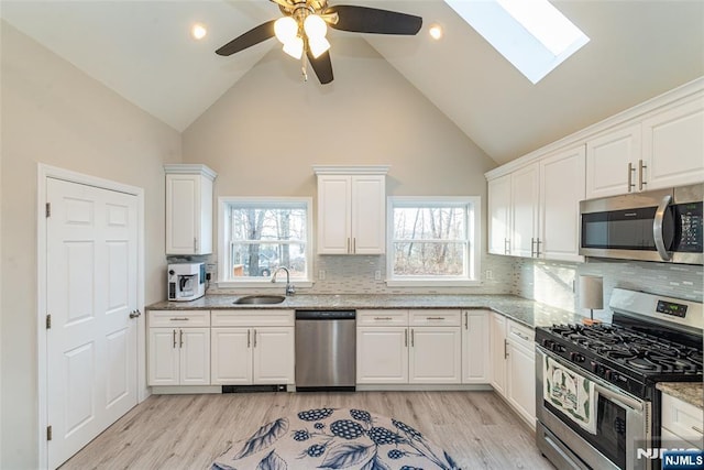 22 Elizabeth Rd, West Milford, NJ 07421 - kitchen featuring stainless steel appliances, a sink, a skylight, high vaulted ceiling, and white cabinets