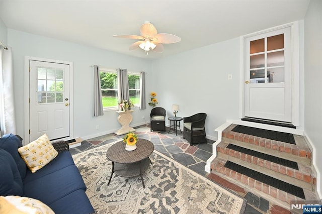 living area with a ceiling fan and baseboards