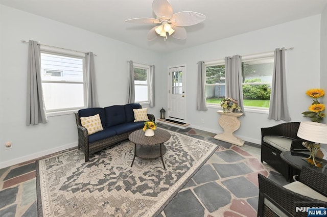 living area with a ceiling fan and baseboards