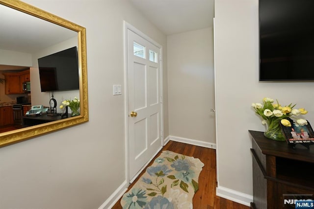 foyer with dark wood-type flooring and baseboards