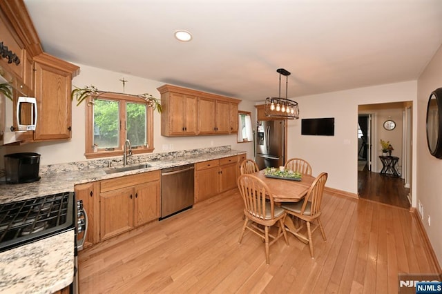 kitchen with appliances with stainless steel finishes, a sink, light wood-style floors, hanging light fixtures, and recessed lighting