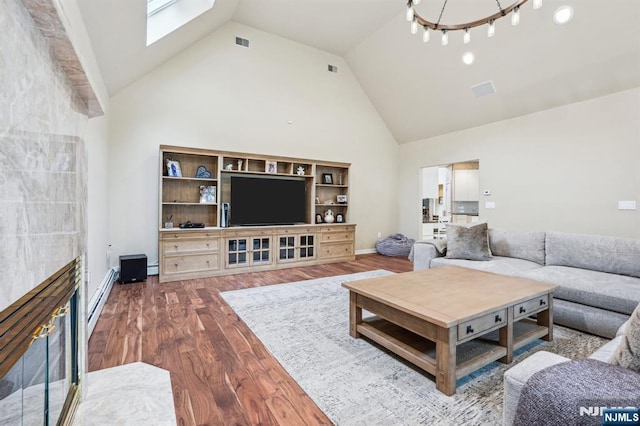 31 Bourbon St, Wayne, NJ 07470 - living area featuring wood finished floors, high vaulted ceiling, a skylight, a baseboard heating unit, and baseboards