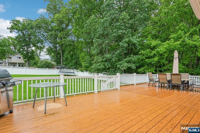 31 Bourbon St, Wayne, NJ 07470 - wooden deck with outdoor dining space, a trampoline, area for grilling, and view of wooded area