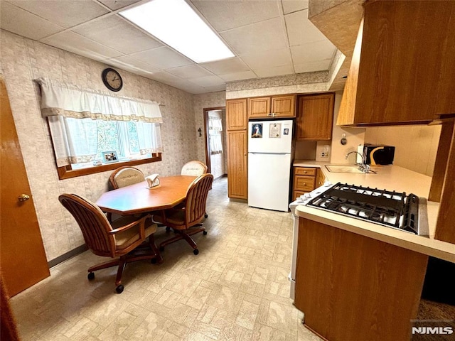 178 Fern Ave, Lyndhurst, NJ 07071 - kitchen featuring freestanding refrigerator, brown cabinetry, light countertops, a paneled ceiling, and gas stove