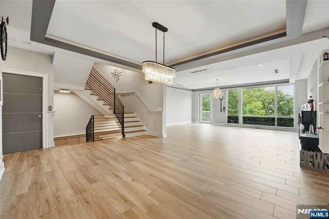 26 Hudson Ter, Edgewater, NJ 07020 - unfurnished living room with a chandelier, light wood finished floors, stairs, and a tray ceiling