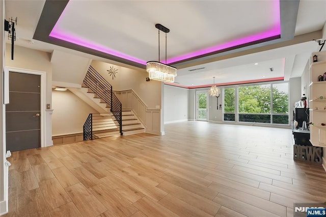 26 Hudson Ter, Edgewater, NJ 07020 - unfurnished living room with a raised ceiling, a chandelier, light wood-style floors, and stairs