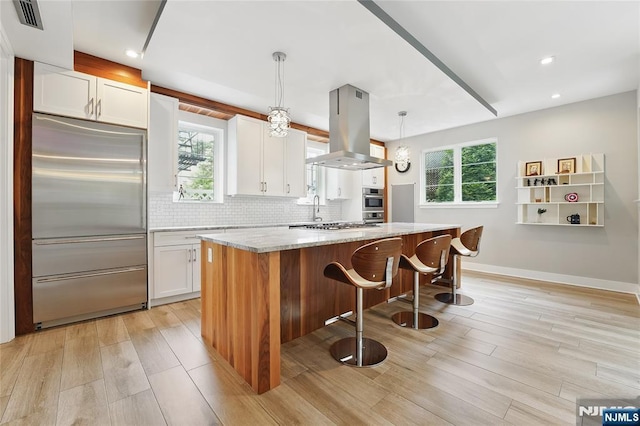 26 Hudson Ter, Edgewater, NJ 07020 - kitchen featuring stainless steel built in refrigerator, island exhaust hood, a kitchen island, white cabinetry, and tasteful backsplash
