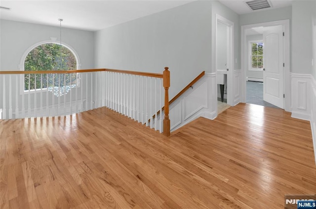 27 Tecumseh Trl, Oakland, NJ 07436 - empty room featuring light wood-type flooring, baseboard heating, and a wainscoted wall