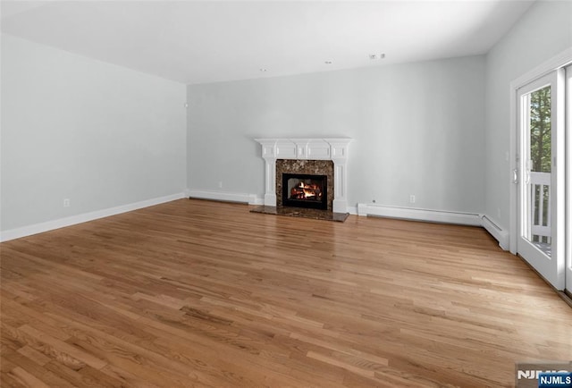 27 Tecumseh Trl, Oakland, NJ 07436 - unfurnished living room featuring light wood-style flooring, baseboards, a premium fireplace, and a baseboard heating unit