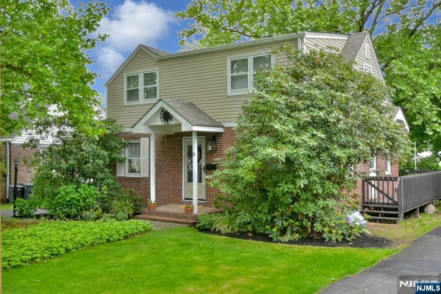 8 Highland Ave, Dumont, NJ 07628 - view of front of home with brick siding, a front yard, and a wooden deck