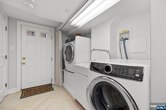 747 Mildred St, Teaneck, NJ 07666 - laundry area with washer and clothes dryer, light tile patterned floors, and cabinet space