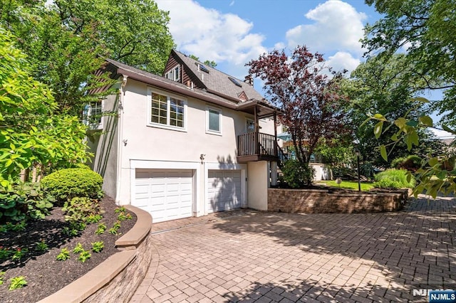 747 Mildred St, Teaneck, NJ 07666 - view of front of house featuring stucco siding, an attached garage, decorative driveway, and a balcony