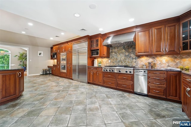 15 Fred St, Old Tappan, NJ 07675 - kitchen featuring built in appliances, wall chimney range hood, tasteful backsplash, glass insert cabinets, and recessed lighting