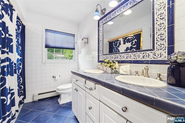 15 Fred St, Old Tappan, NJ 07675 - full bath featuring a baseboard heating unit, tile walls, tile patterned flooring, toilet, and double vanity