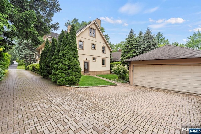 296 Highfield Ln, Nutley, NJ 07110 - view of home's exterior with a garage, stucco siding, a yard, and a chimney