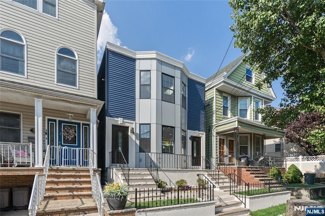 133 4th St, Bayonne, NJ 07002 - view of property featuring covered porch, a fenced front yard, and stairway