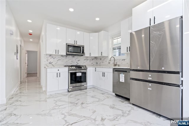 133 4th St, Bayonne, NJ 07002 - kitchen with appliances with stainless steel finishes, light countertops, backsplash, white cabinets, and light marble finish floors