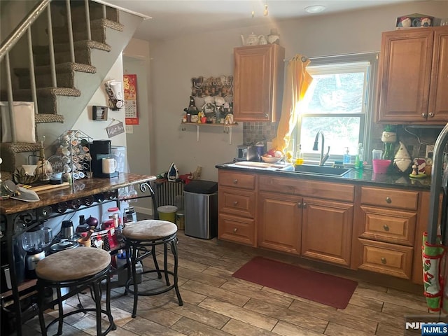 67-69 Garret St, Paterson, NJ 07501 - kitchen with a sink, light wood finished floors, decorative backsplash, brown cabinetry, and dark countertops