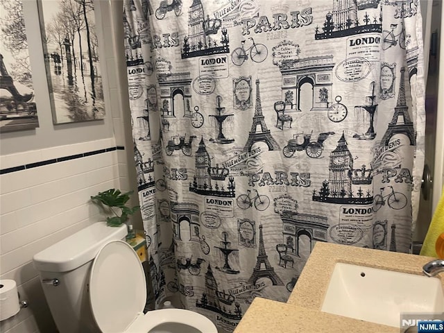 67-69 Garret St, Paterson, NJ 07501 - bathroom with tile walls, toilet, a sink, a wainscoted wall, and a shower with curtain