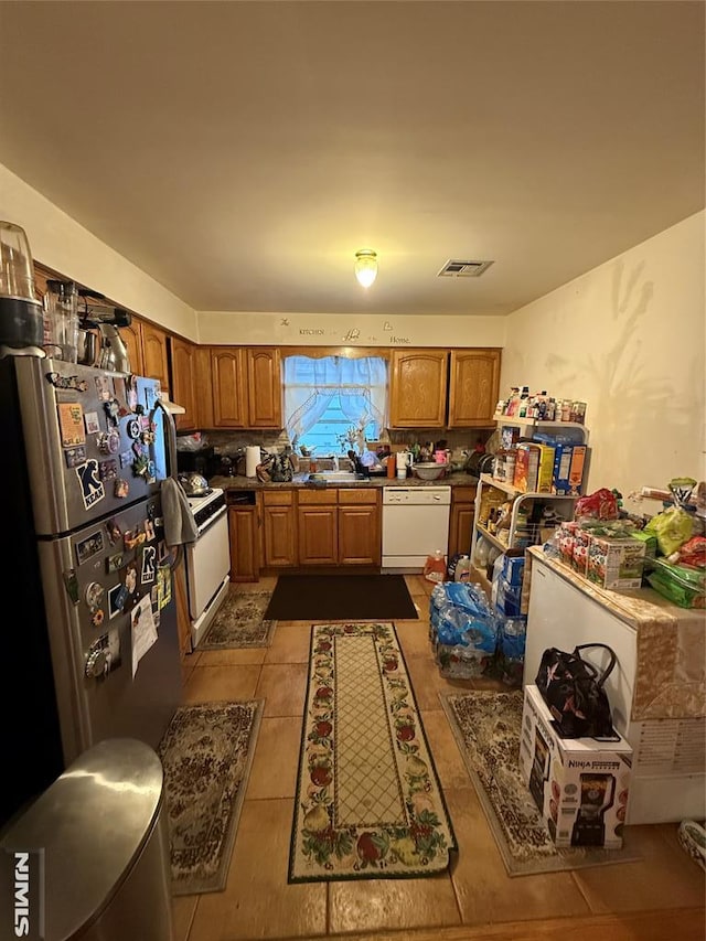 74 Kenmore Ave, Newark, NJ 07106 - kitchen with white appliances, brown cabinets, a sink, tile patterned flooring, and dark countertops